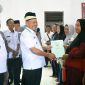 Bupati Lamtim, H. M. Dawam Rahardjo, menyerahkan langsung sertifikat PTSL kepada masyarakat desa sumur bandung. (*Ist) 