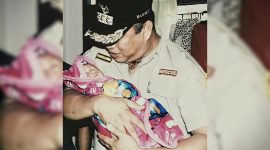Dr. Ir. H. Ruksamin, S.T., M.Si., IPU., ASEAN Eng., terlihat dengan penuh kasih sayang menggendong salah satu bayi warga.